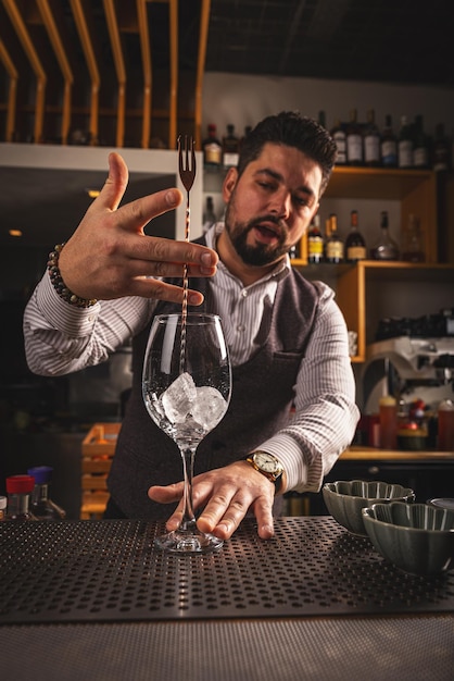 Le barman mélange des cubes de glace.