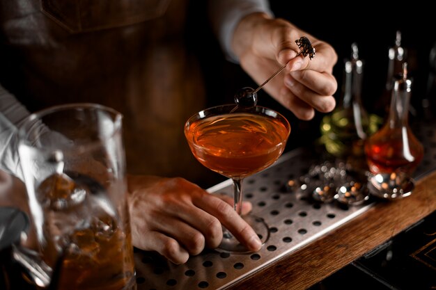 Barman met les olives dans un verre avec un cocktail