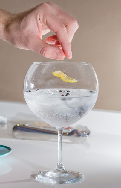 Barman mettant le zeste de citron pour préparer le gin tonic