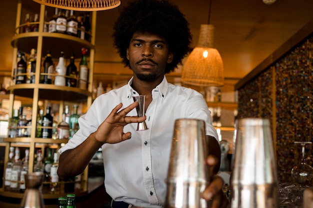 Photo un barman noir jouant avec un kit de cocktail en métal.