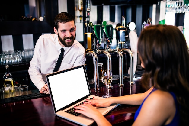 Barman parle au client à l&#39;aide d&#39;un ordinateur portable dans un bar