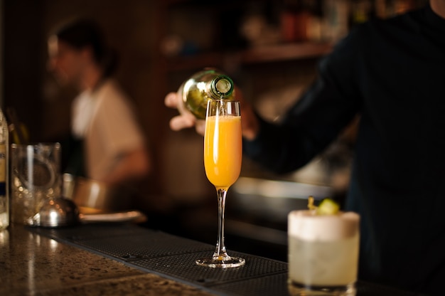 Barman part versant une boisson fraîche et orange vif dans un verre