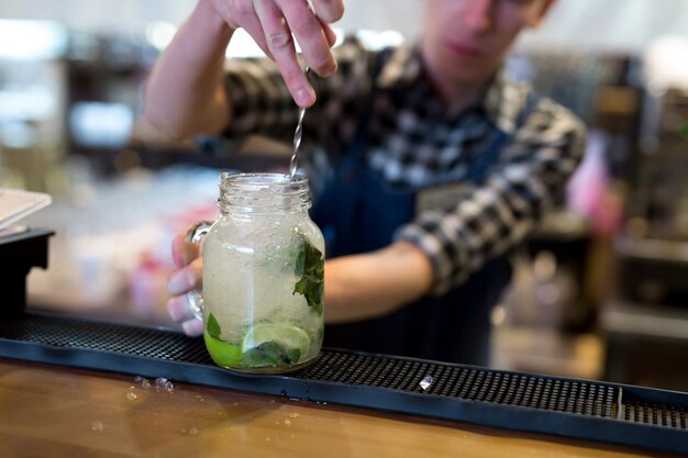 Le barman pile de la glace pour un cocktail Mojito au bar.