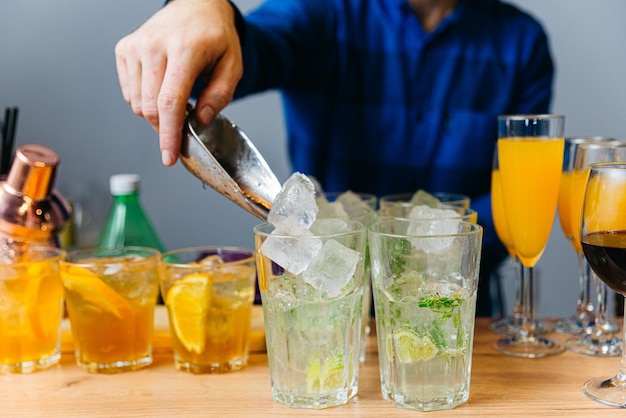 Barman préparant un cocktail au citron vert citron orange et glace