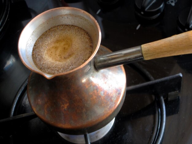 Le barman prépare une boisson savoureuse et chaude à partir de cuivre. Le turc fait bouillir de l'eau pour le café sur un petit feu à Cezve. Le café turc est fabriqué à partir du cuivre organique.