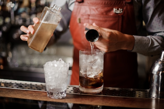 Le barman prépare un cocktail alcoolisé avec de la glace