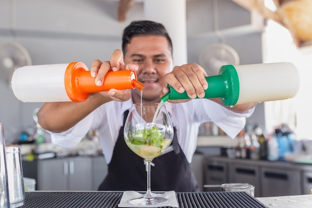 Le barman prépare un cocktail au comptoir du bar.