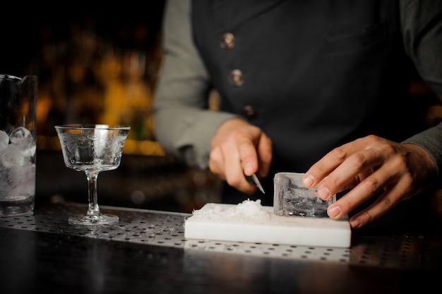 Barman prépare un morceau de glace pour faire un cocktail