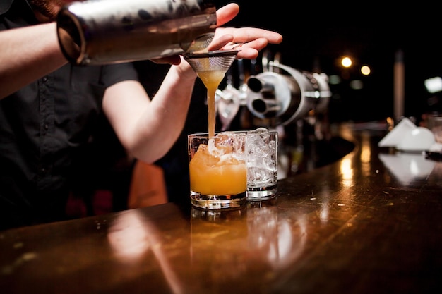 Un barman professionnel verse de la glace dans un verre pour boire le temps d'une fête dans une discothèque