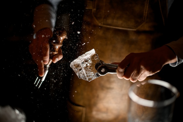 Barman en tablier de cuir faisant un écrasé avec une fourchette spéciale