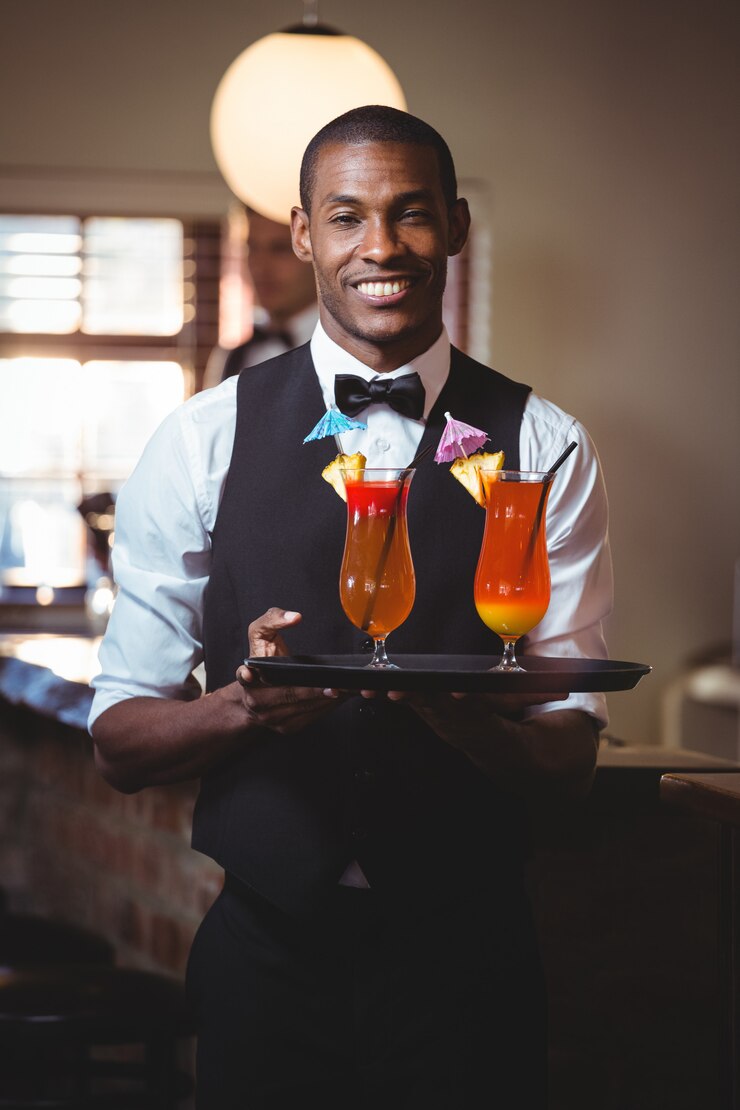Barman tenant un plateau de service avec deux verres de cocktail