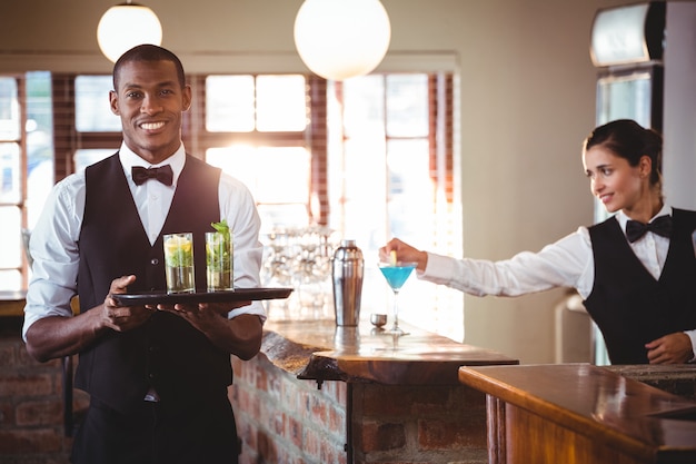 Barman tenant un plateau de service avec deux verres à cocktail