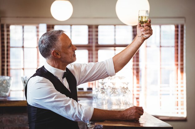 Barman tenant un verre de vin au comptoir du bar