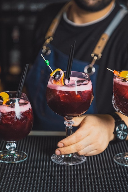 Barman tient un cocktail avec des fruits à la main Pas de visage Mise au point sélective