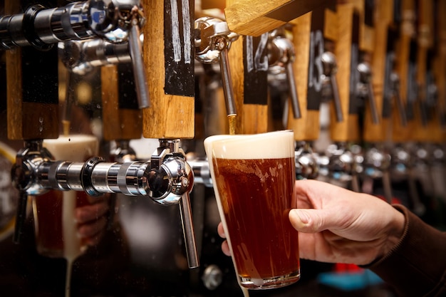 Barman versant de la bière fraîche dans le verre au pub, bar