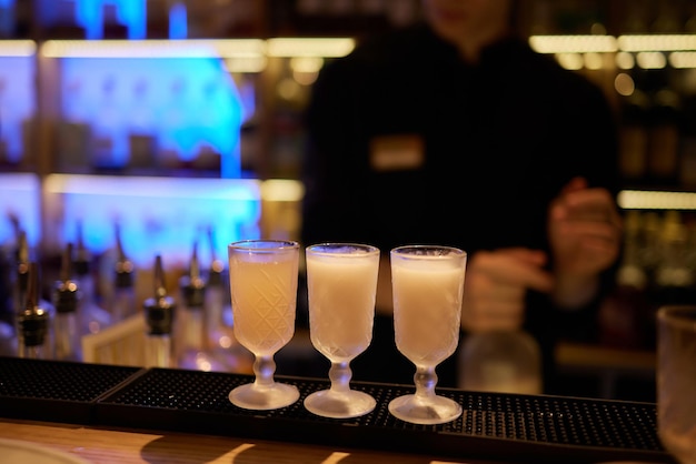 Barman versant une boisson alcoolisée forte dans de petits verres sur des shots de bar