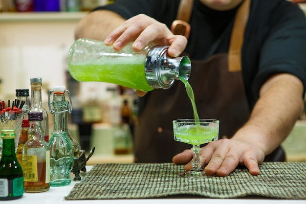 Barman versant un cocktail rose