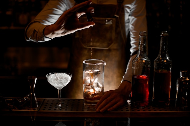 Barman versant une essence de la petite bouteille en verre