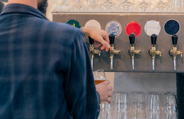 Barman versant une grande bière blonde dans un choix de bière au bar