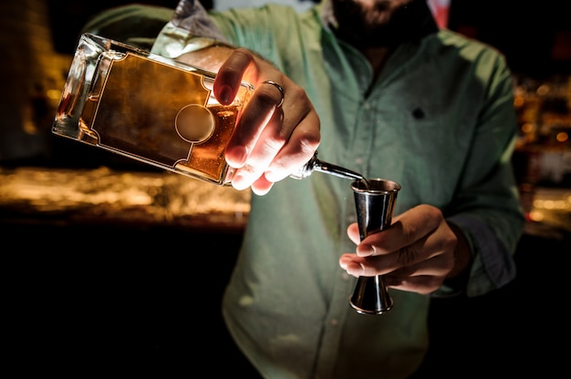 Barman versant un sirop pour faire un cocktail