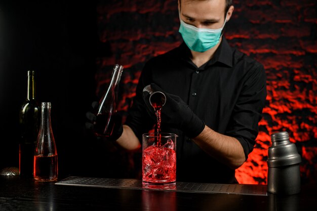 Le barman verse attentivement une boisson alcoolisée dans un grand verre de glace