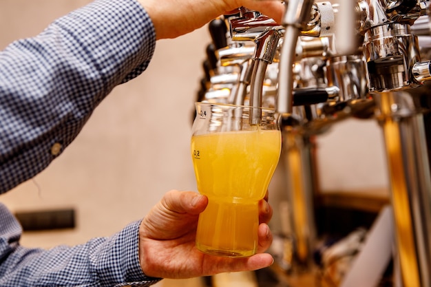 Le barman verse de la bière légère fraîche du robinet dans le pub