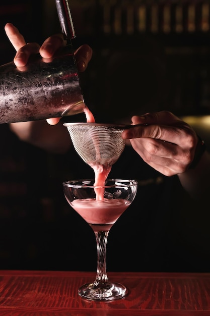 Le barman verse un cocktail alcoolisé dans un verre à longue tige Reste dans un bar-restaurant de discothèque