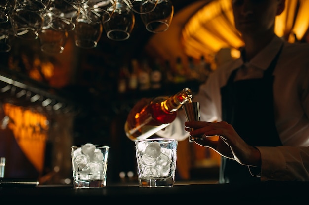 Le barman verse du whisky sur le bar