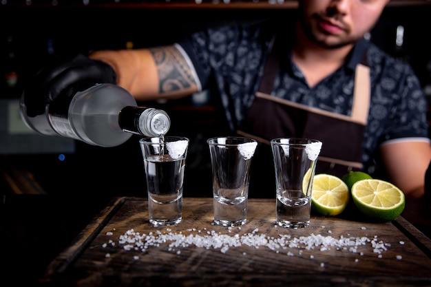 Barman verse de l'esprit dur dans de petits verres