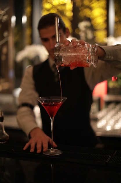 Le barman verse un verre au comptoir du bar.