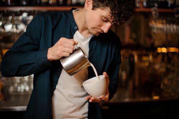 Barman verser du lait du pichet dans une tasse