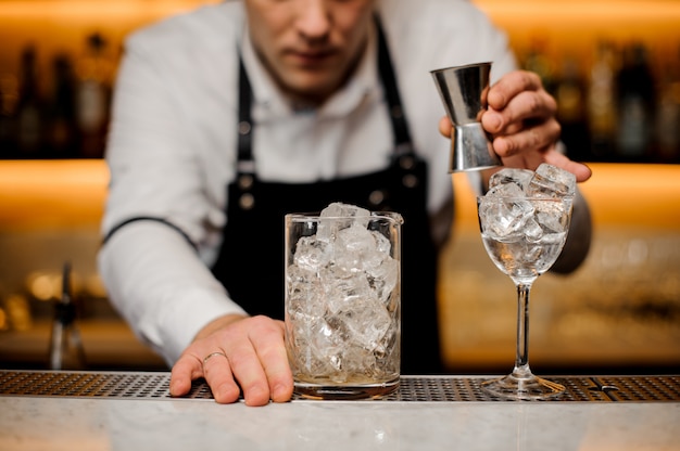 Barman vêtu d'une chemise blanche avec un verre avec des glaçons