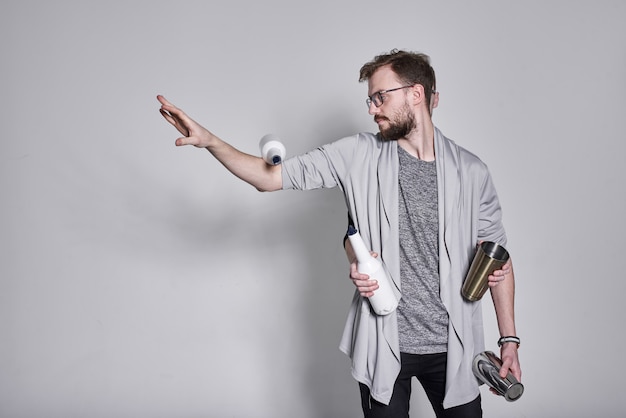 Barmen homme jonglant avec des bouteilles et secouant sur le mur blanc, des jumeaux