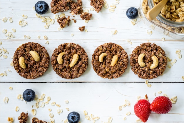 Barre au chocolat au granola maison et baies fraîches sur la table en bois avec espace.