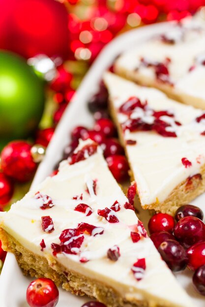 Barre de bonheur aux canneberges faite de morceaux de chocolat blanc et de canneberges séchées, garnie d'un glaçage au fromage à la crème sucré.