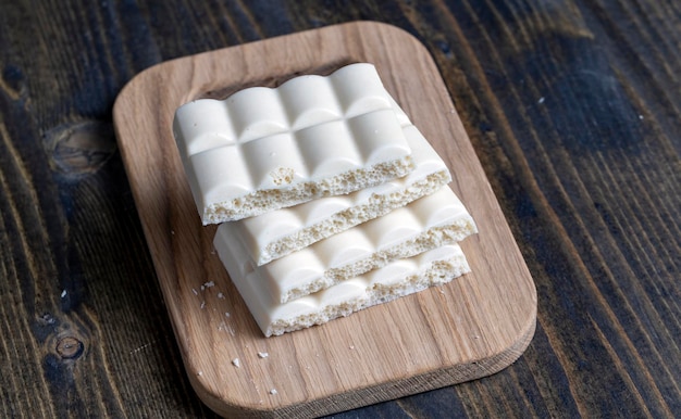 Barre de chocolat blanc cassée en morceaux et morceaux sur la table