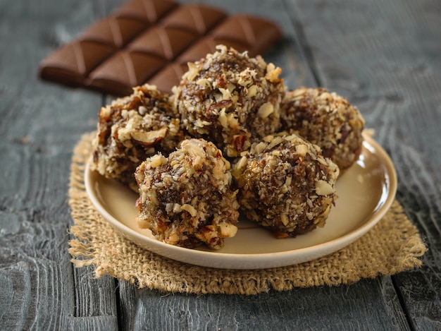 Une Barre De Chocolat Et Des Boules De Noix, De Fruits Secs Et De Chocolat Sur Une Table Noire. Délicieux Bonbons Faits Maison.