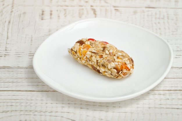 Barre de muesli sur une soucoupe blanche. Table en bois blanc