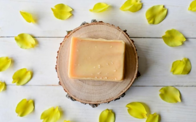 Photo une barre de savon jaune sur une plate-forme ronde en bois clair arrière-plan avec des pétales jaunes vibrants