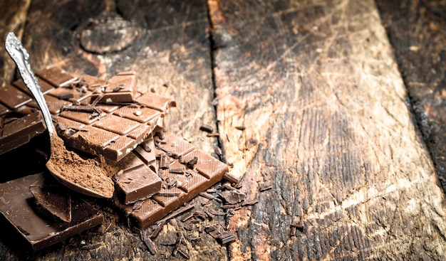 Barres de chocolat au cacao en poudre. Sur une table en bois.