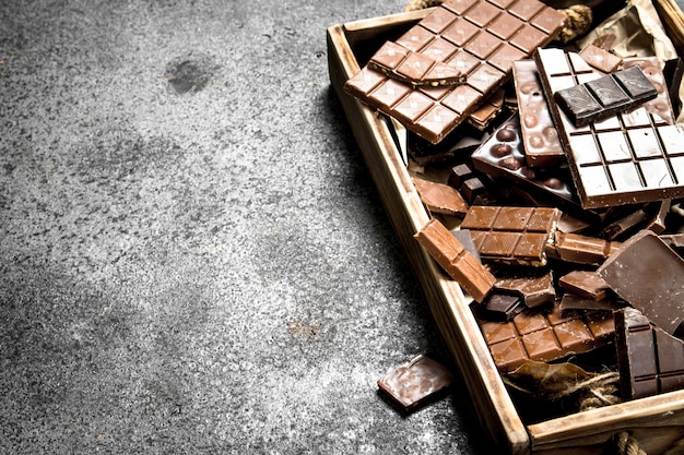 Barres de chocolat cassées sur plateau en bois. Sur un fond rustique.