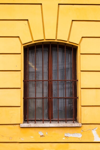 Barres sur la fenêtre vintage et le mur jaune à l'extérieur