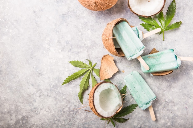 Barres de glace à la crème glacée avec des tranches de noix de coco, du cannabis sur fond de béton.