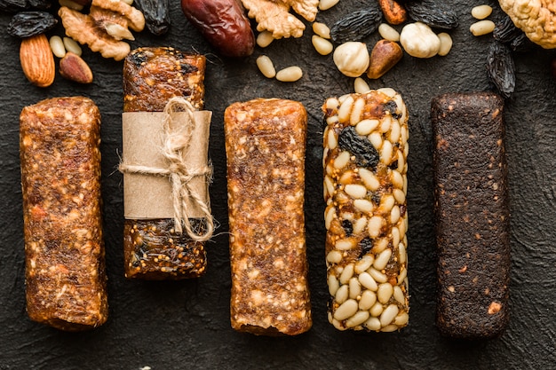 Photo barres de miel aux arachides, graines de sésame et tournesol noix de caramel. collations de graines, noix et graines de sésame avec du miel sur un fond en bois. noix sucrées.