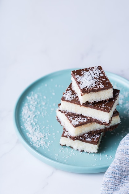 Barres de noix de coco végétalienne bio énergie saine fait maison avec du chocolat sur une table de cuisine