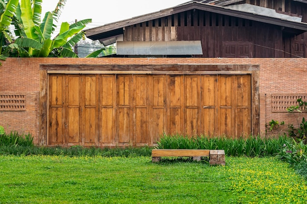 La barrière de clôture de mur de briques est conçue avec un trou sur le dessus du mur dans un style asiatique avec un champ d'herbe de jardin au premier plan