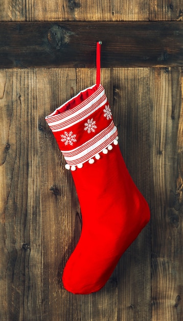 Bas de Noël. Chaussette rouge suspendue au-dessus d'un fond en bois rustique. Décoration de vacances