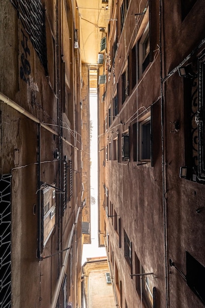 En bas de la rue sombre étroite entre les vieux bâtiments résidentiels dans le quartier médiéval de Gênes en Italie