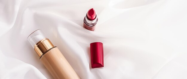 Base de fond de teint liquide de maquillage de bouteille de crème tonale beige et rouge à lèvres rouge sur fond de soie produits cosmétiques comme conception de vacances de marque de beauté de luxe