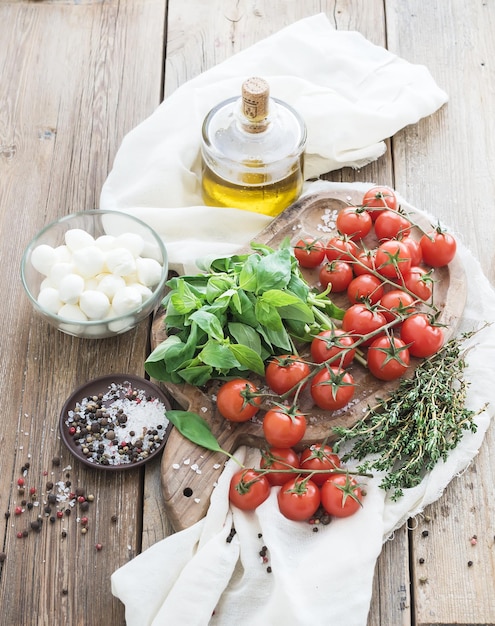 Basilic Tomates Cerises Mozarella Huile D'olive Sel épices Sur Planche à Découper Rustique Sur Fond De Bois Ancien